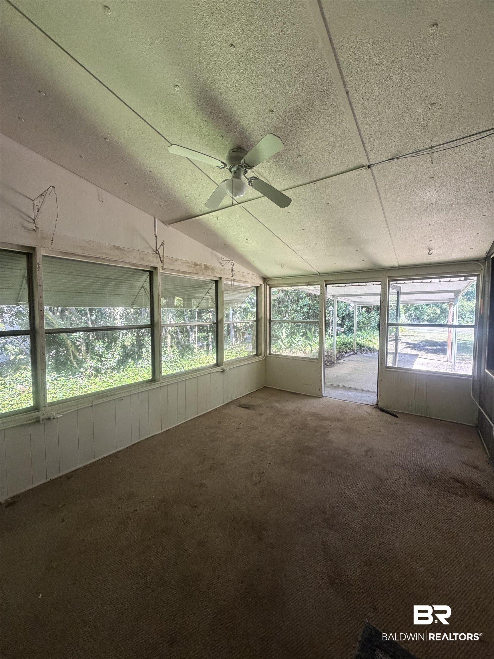 Image 4: Enclosed screened porch with a ceiling fan, carpet flooring, and white paneling
