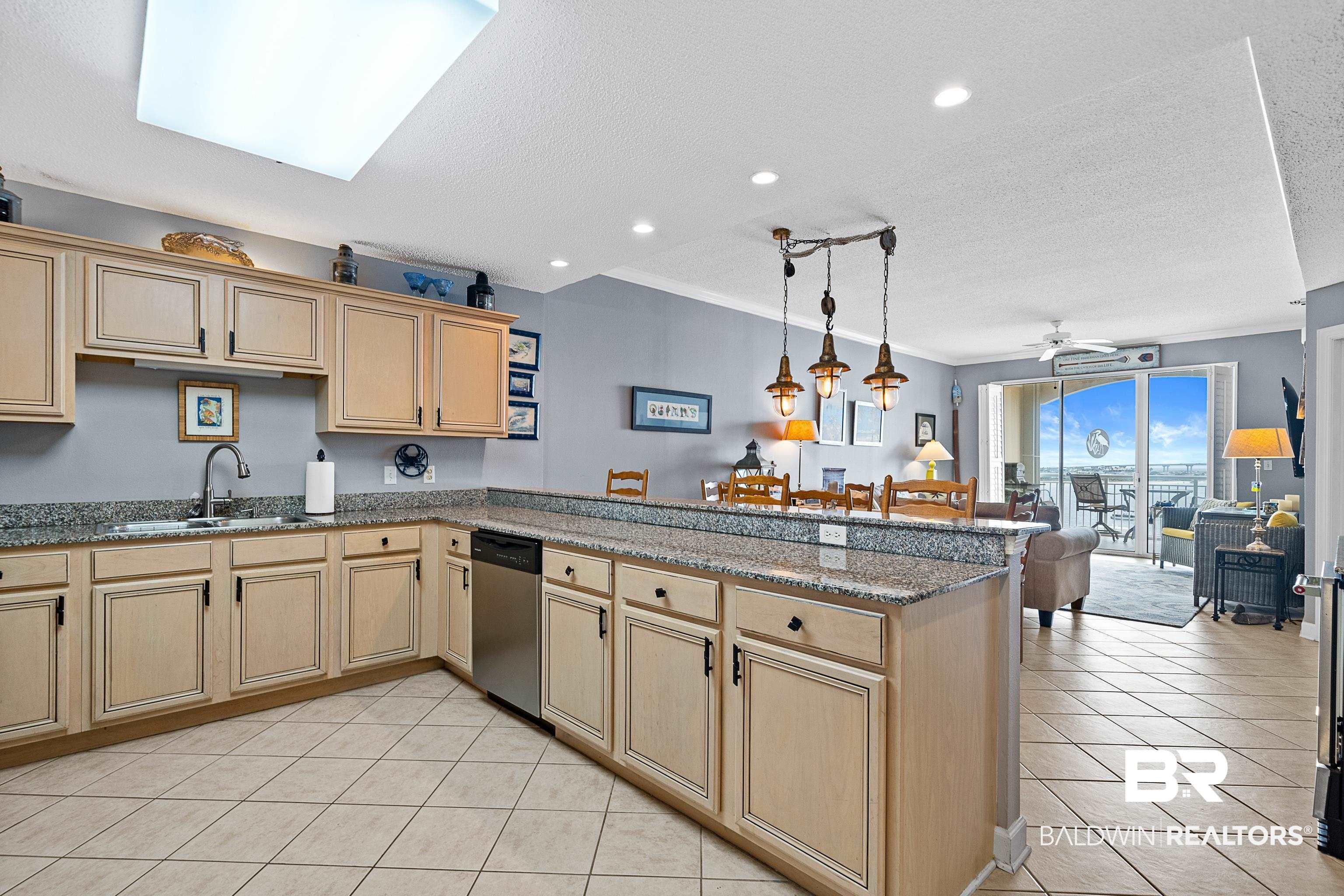 Image 3: Kitchen featuring light tile patterned floors, dark stone countertops, a ceiling fan, a textured ceiling, and open floor plan