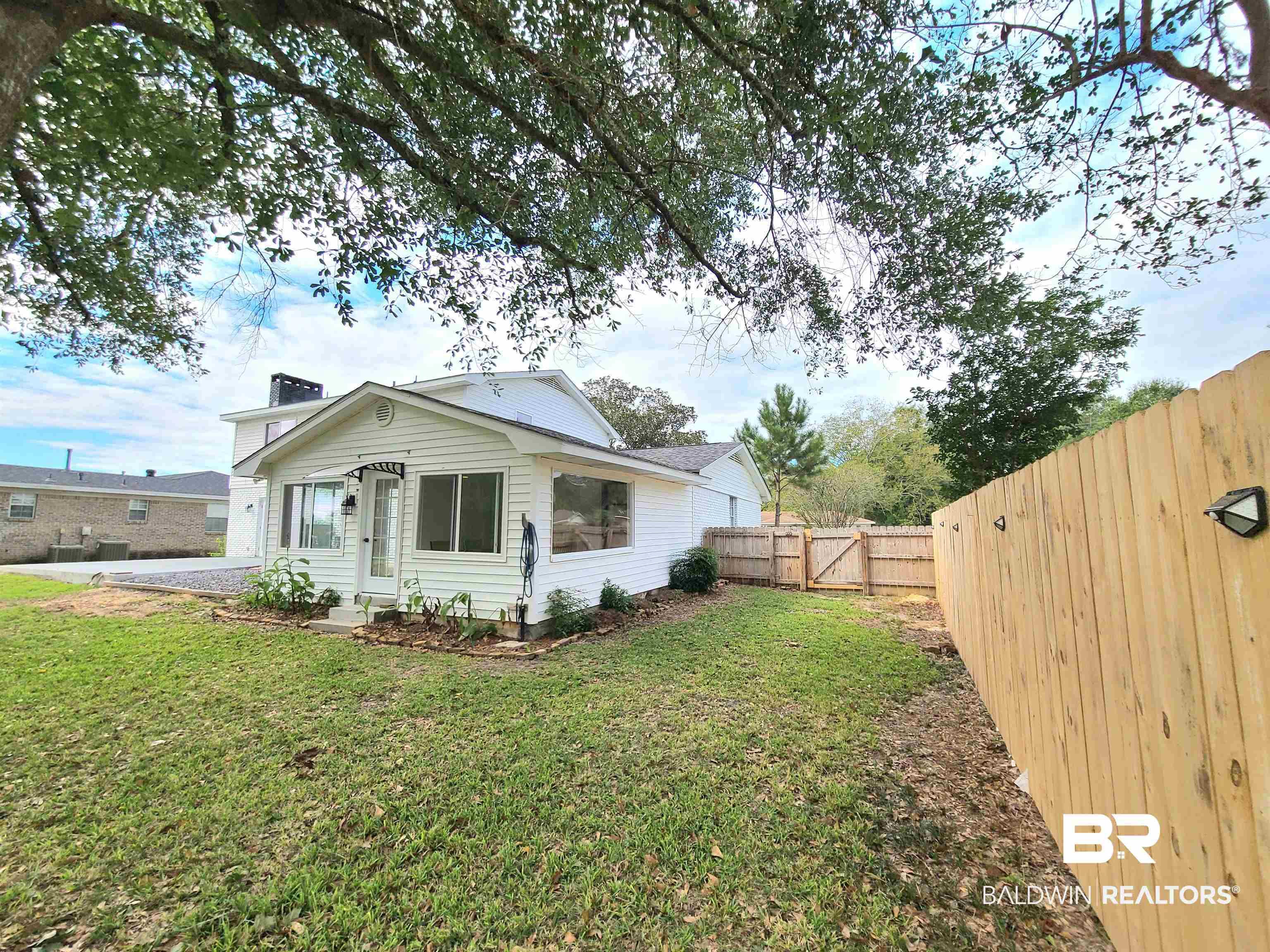 Image 3: View of side of property with a gate, a fenced backyard, and a chimney