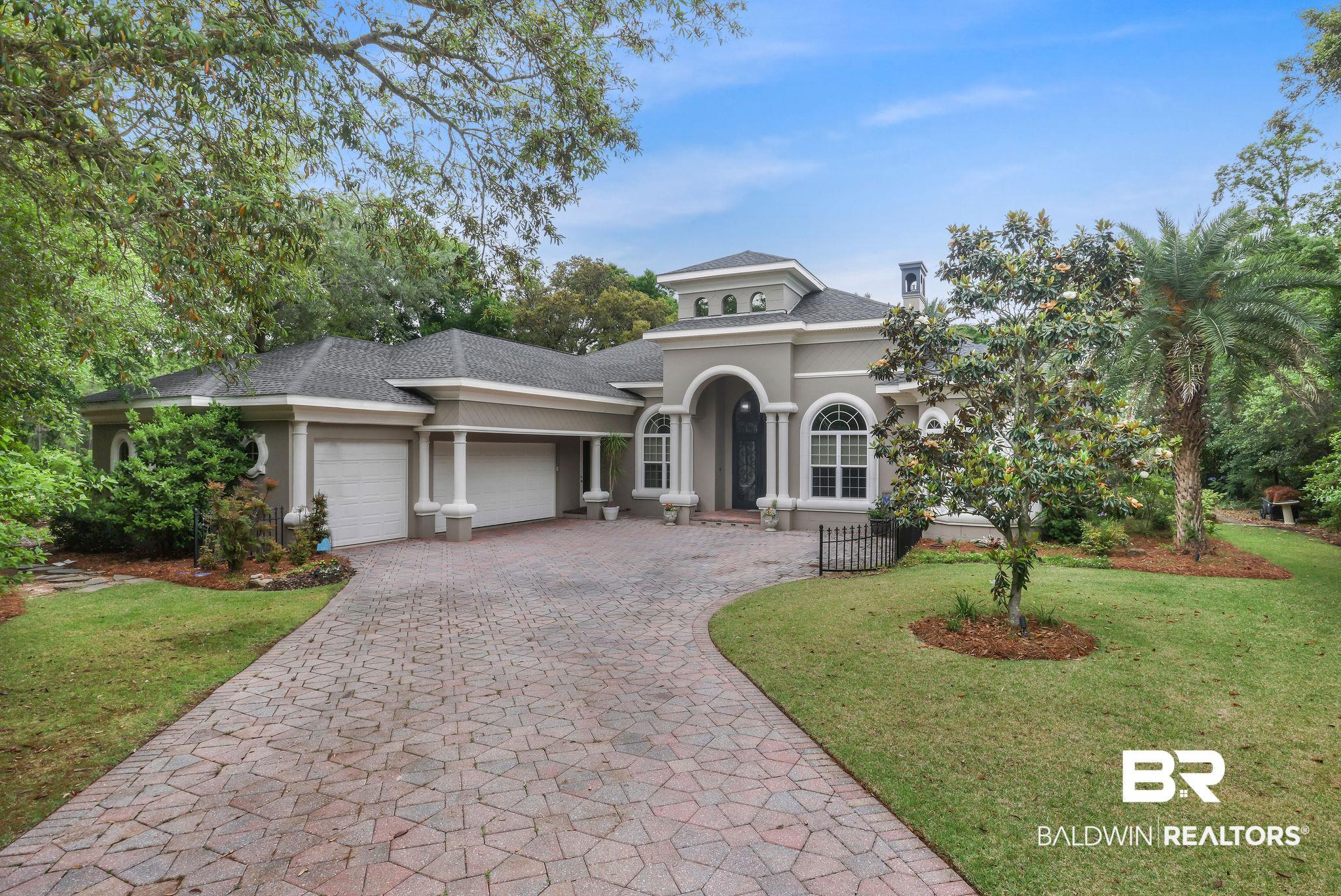 Image 2: Stucco exterior featuring a paver driveway, multiple garage bays, arched windows, and established landscaping