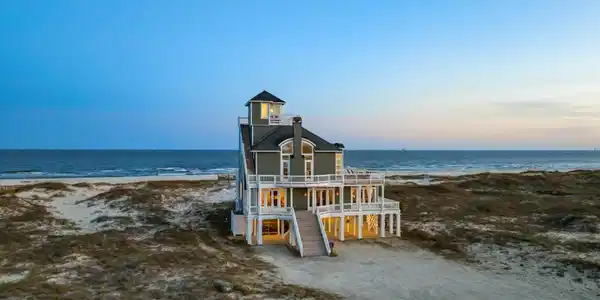 Image 2: Coastal residence featuring multiple levels of outdoor decking, a distinctive cupola, and direct beach access