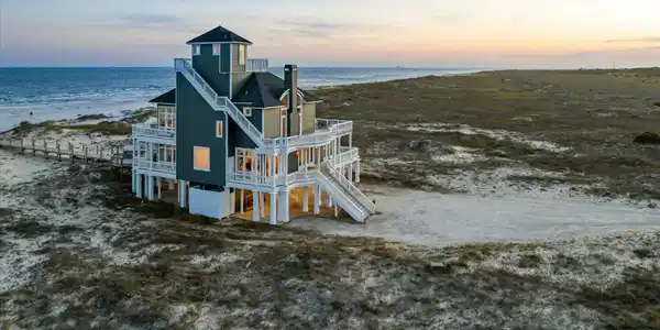 Image 3: Multi-level coastal residence featuring an elevated foundation, multiple expansive balconies, and a distinctive cupola