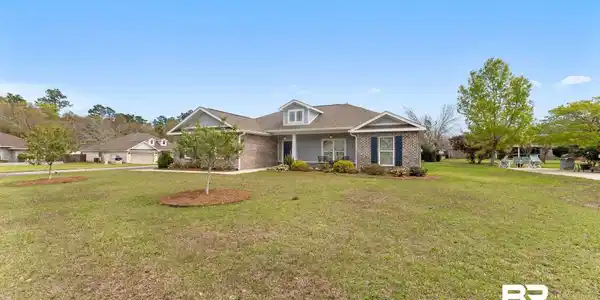 Image 3: View of front of home with brick siding, covered porch, and a front lawn