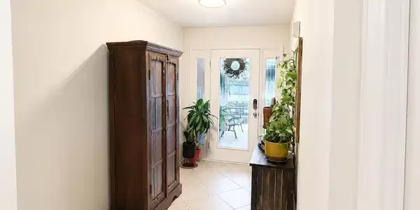 Image 4: Entryway with light-colored tile flooring, white walls, and a ceiling with an open beam feature