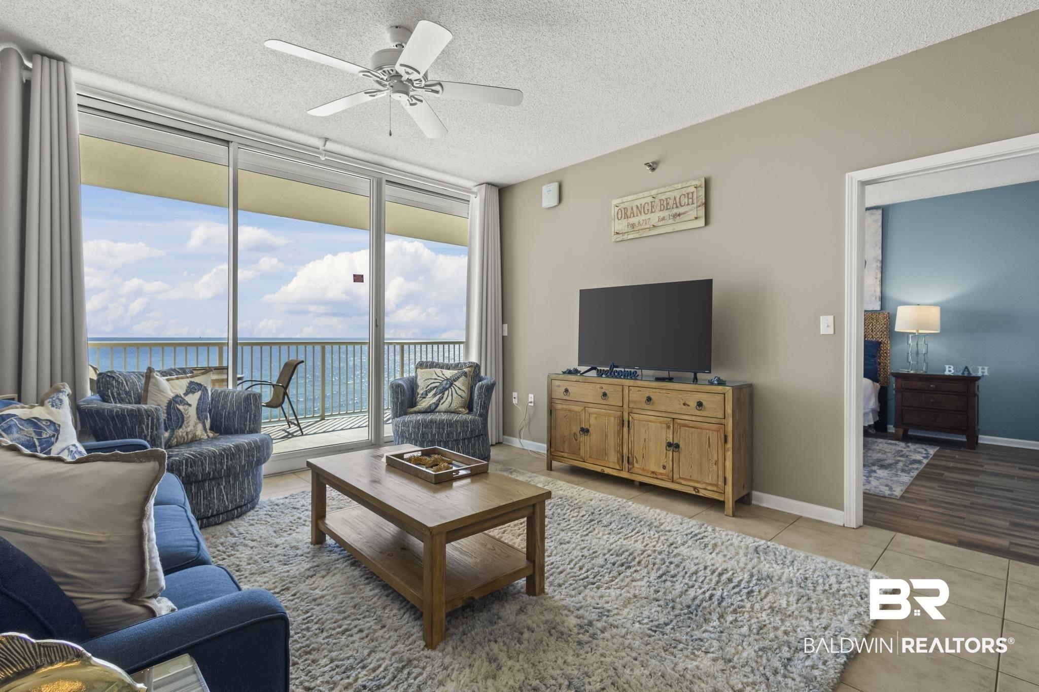 Image 4: Living area featuring floor to ceiling windows, a textured ceiling, light tile patterned flooring, and a ceiling fan