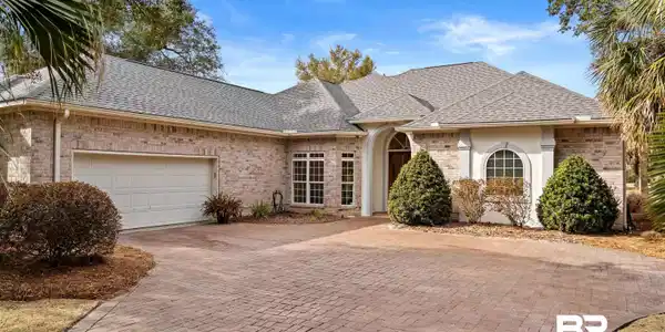 Image 4: View of front facade featuring brick siding, roof with shingles, decorative driveway, and a garage