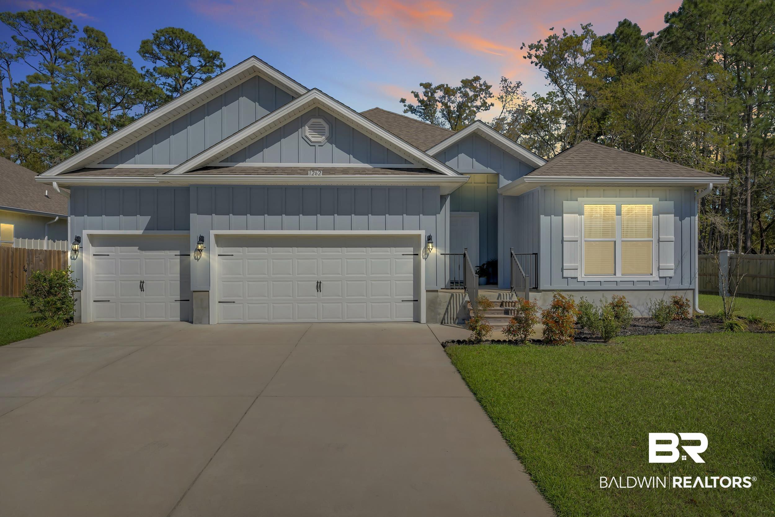 Image 2: View of front of house featuring a garage, concrete driveway, a shingled roof, and board and batten siding