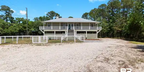 Image 3: Two-story residence featuring a full-width upper balcony and a lower porch, both with white railings