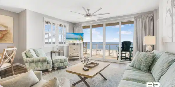Image 2: Living area featuring wood-finish flooring, a ceiling fan, and sliding glass doors opening to a balcony with an ocean backdrop