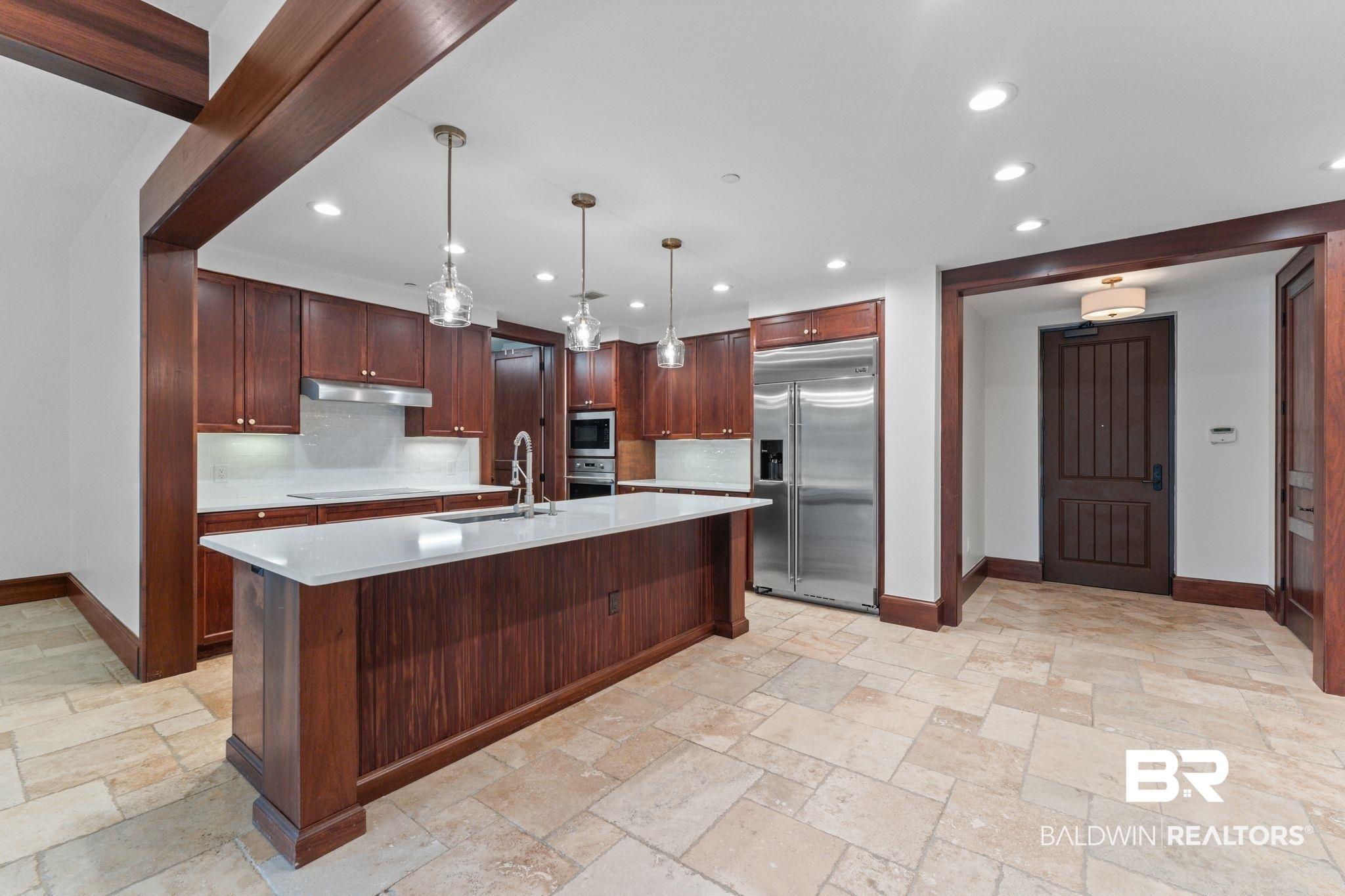 Image 4: Kitchen with decorative light fixtures, built in appliances, a center island with sink, decorative backsplash, and recessed lighting