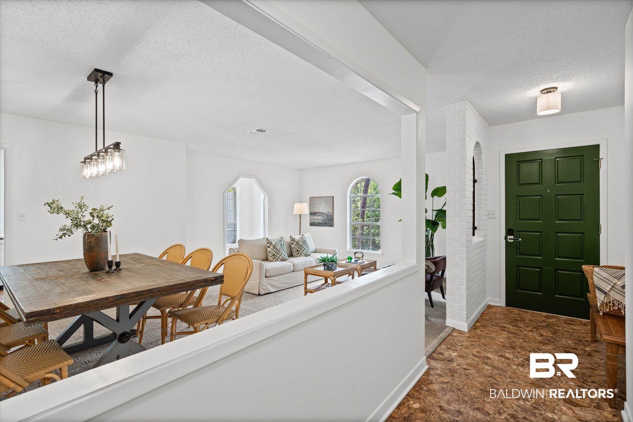 Image 2: Entryway featuring a dark green paneled door, wood-finish flooring, and a white brick-finish accent wall