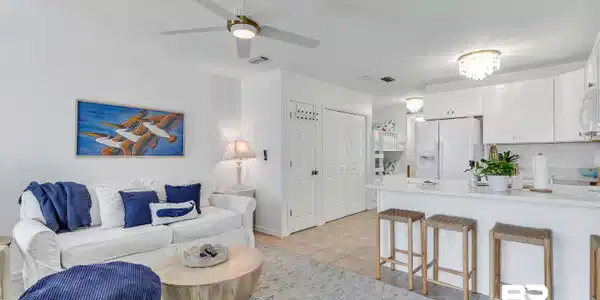 Image 3: Open-concept living area featuring a kitchen island with seating, white cabinetry, integrated appliances, and recessed lighting