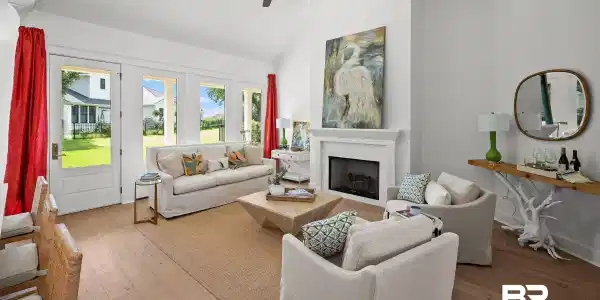 Image 2: Spacious living area featuring high vaulted ceilings, multiple glass-paneled doors, wood-finish flooring, a built-in fireplace with a mantel, and a ceiling fan