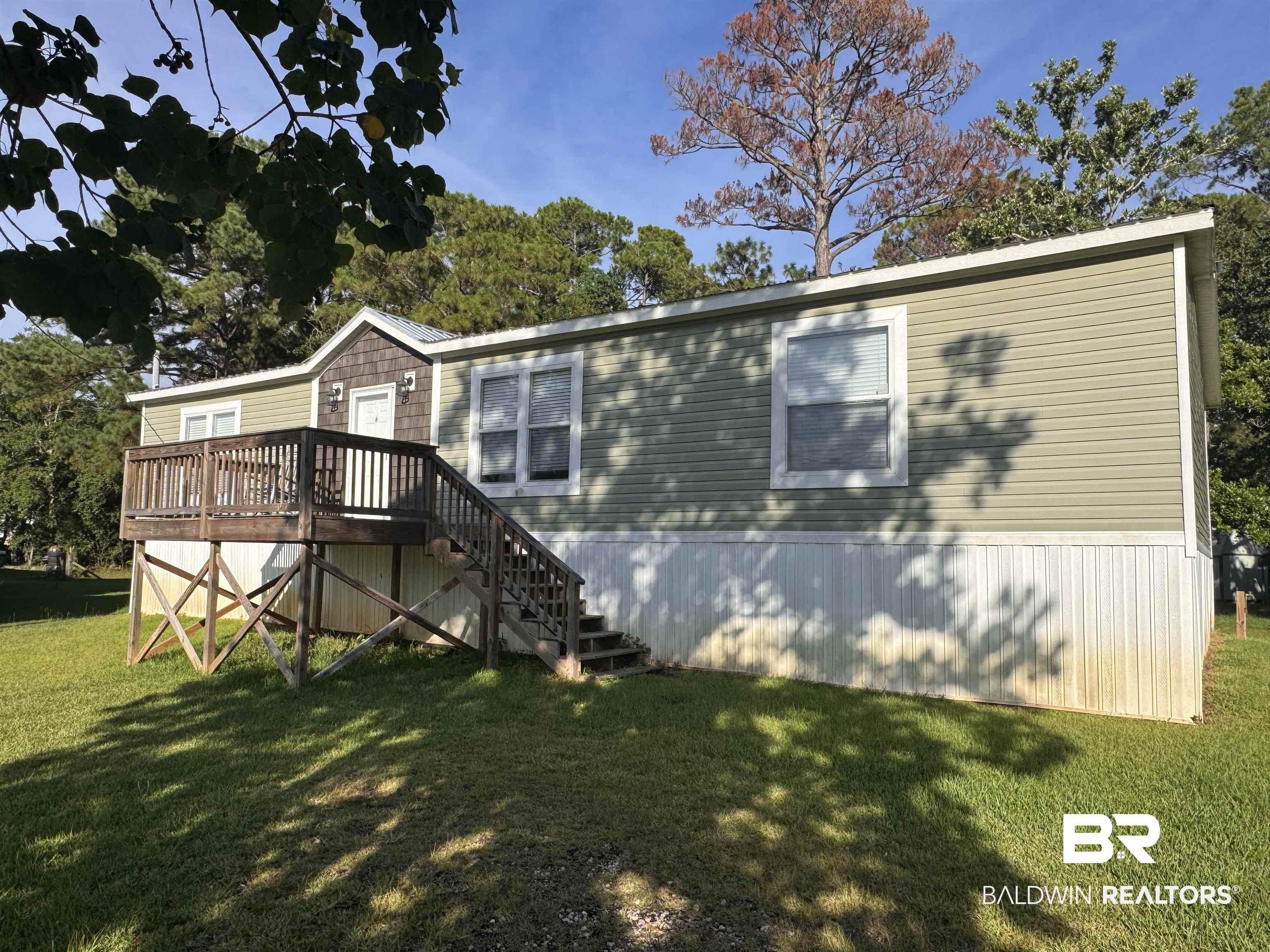 Image 1: View of front facade with a wooden deck and a front yard