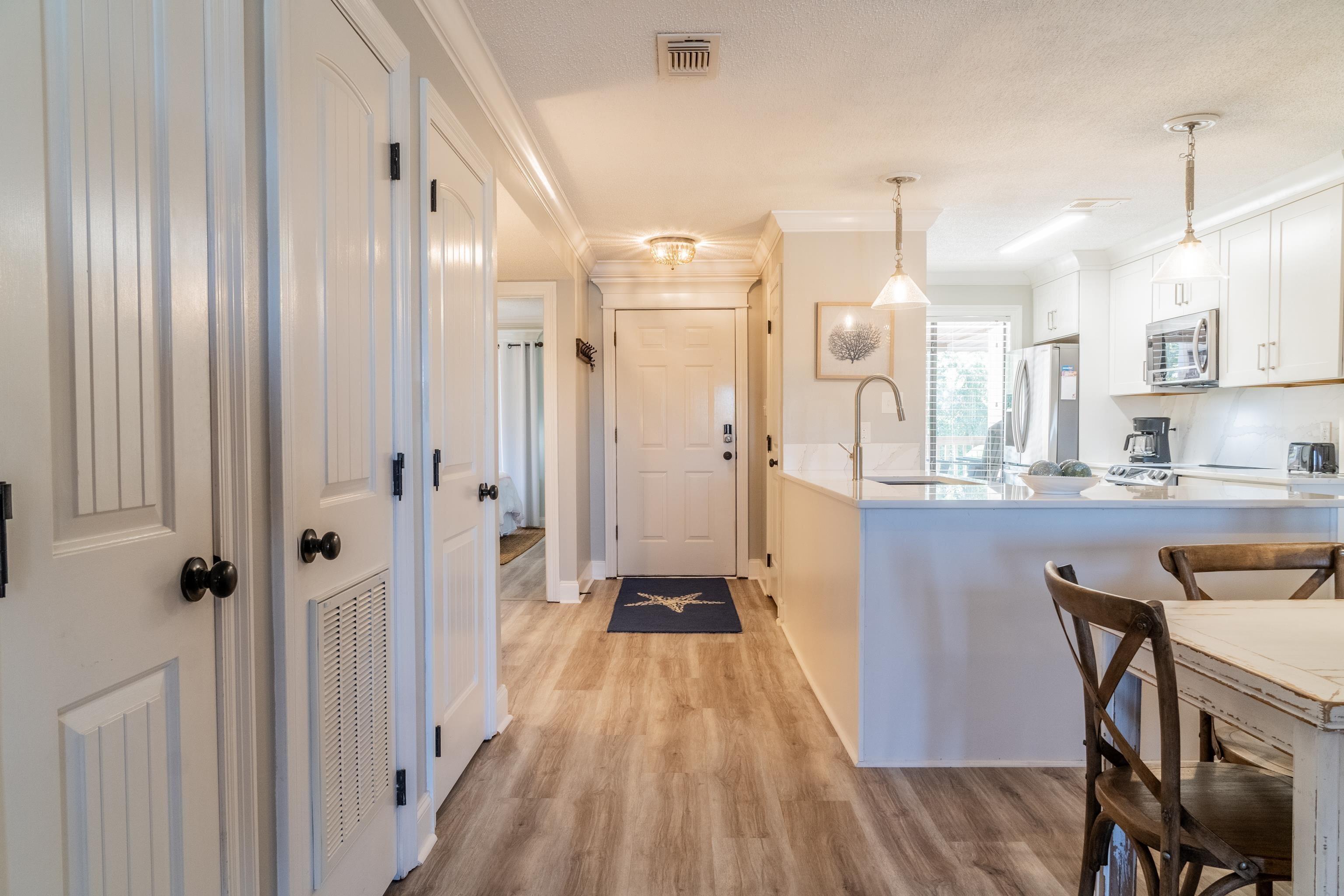 Image 3: Kitchen featuring white cabinetry, light wood-style floors, pendant lighting, stainless steel appliances, and a kitchen breakfast bar