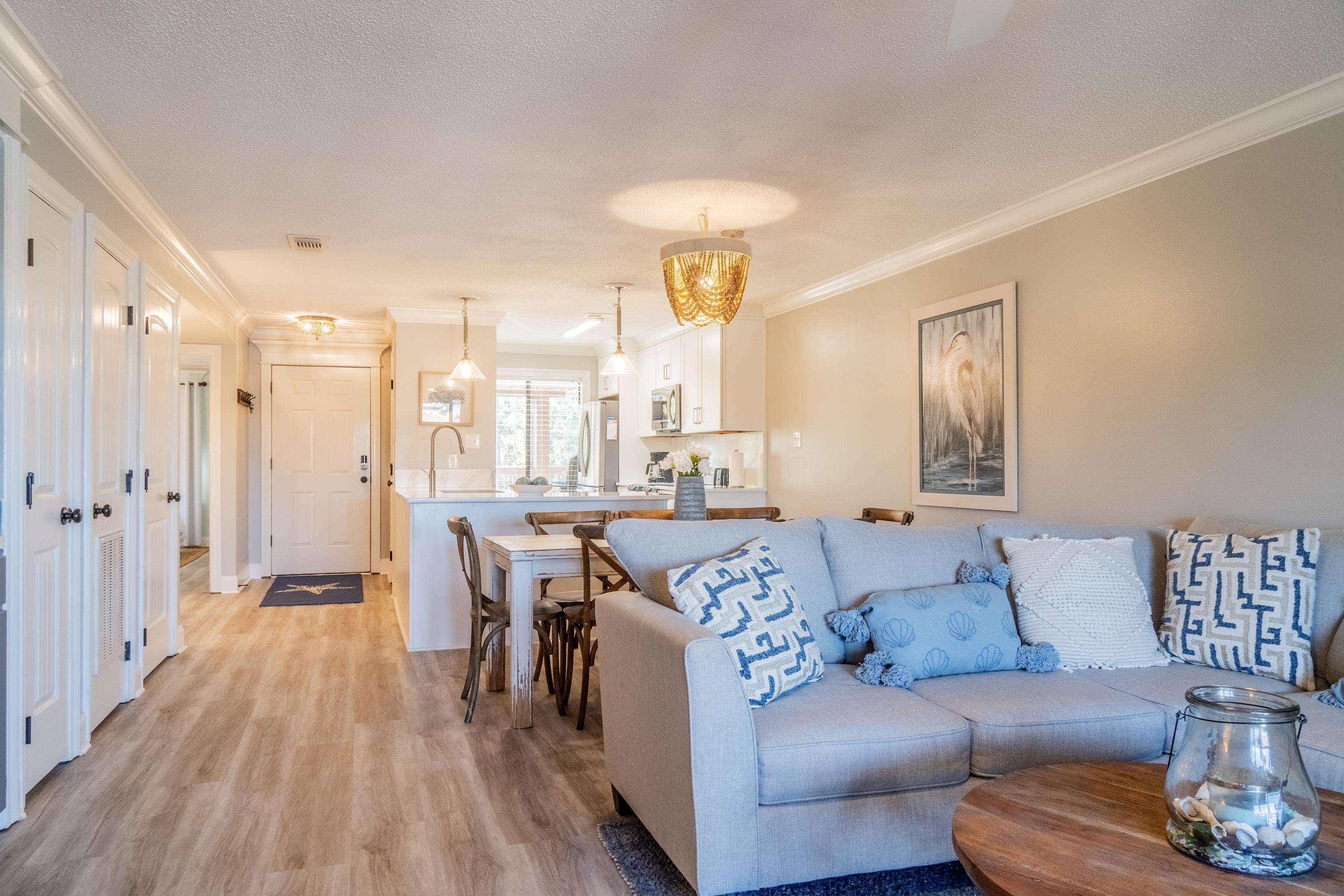 Image 4: Living area with light wood-type flooring, crown molding, a textured ceiling, and a chandelier