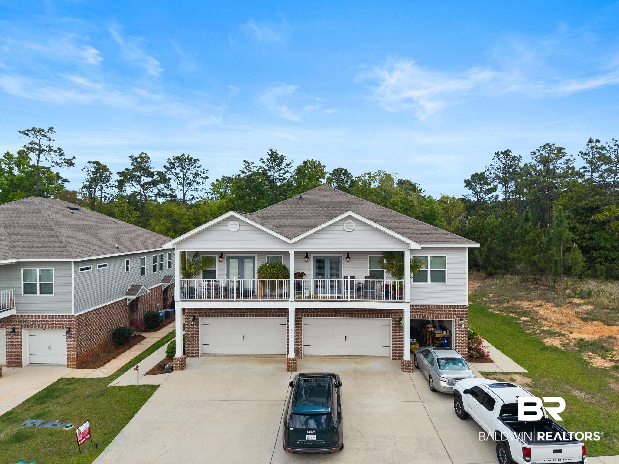 Image 2: View of front facade featuring a garage, brick siding, driveway, and a balcony