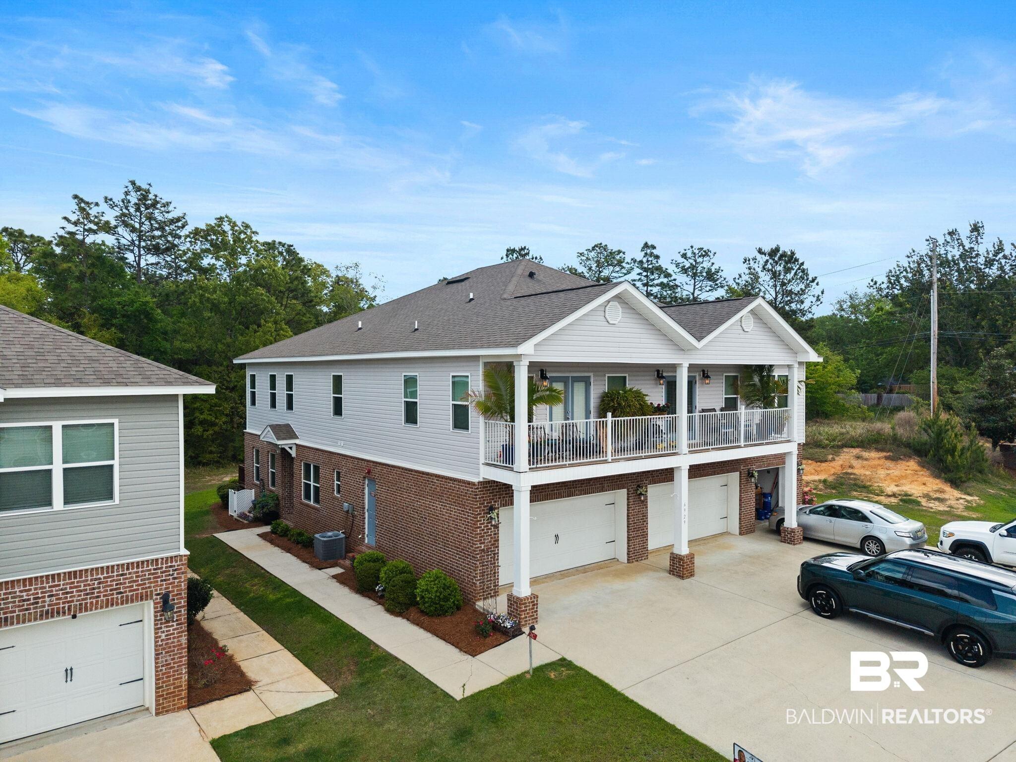Image 3: Coastal inspired home with an attached garage, a balcony, concrete driveway, and brick siding