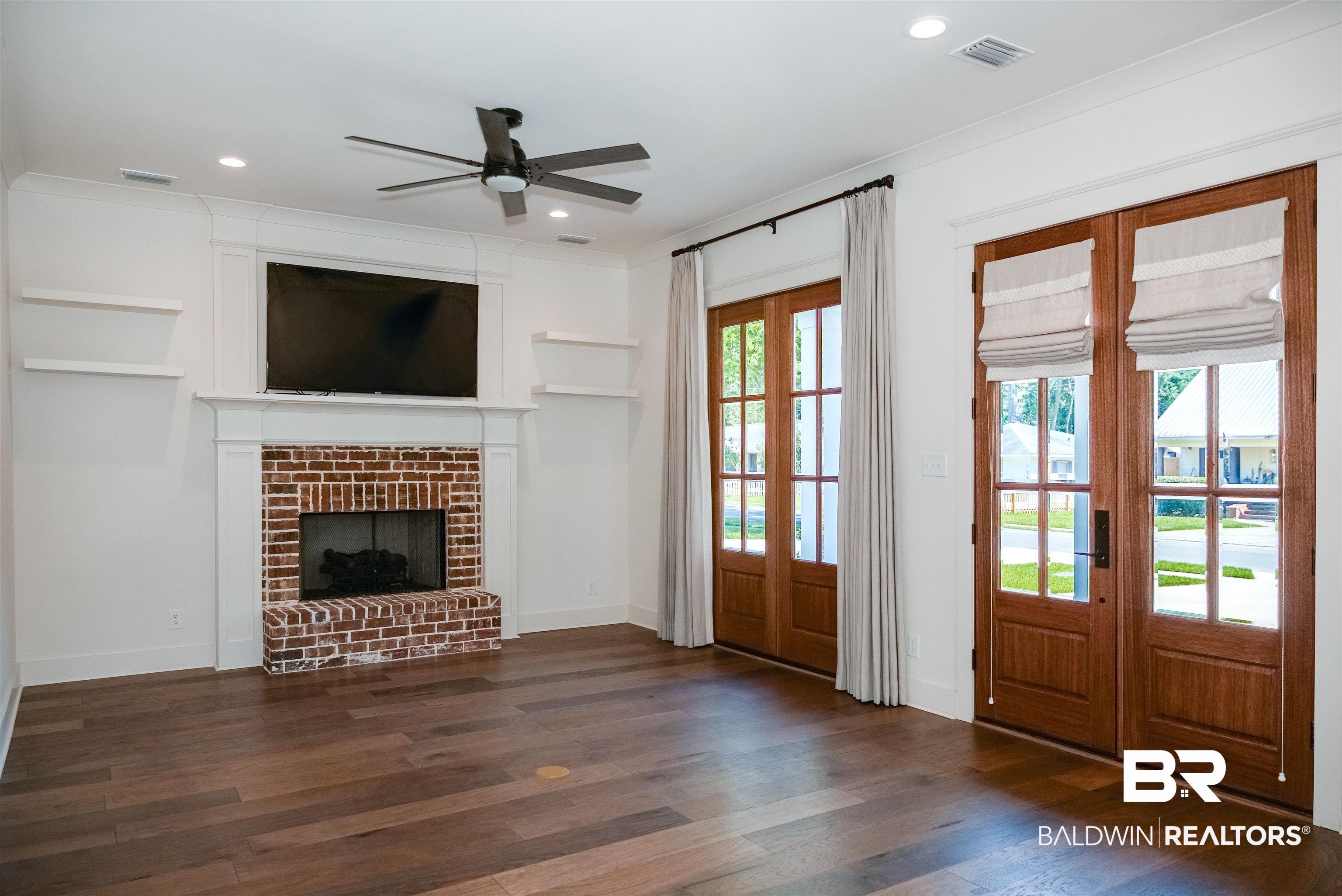 Image 4: Living space featuring rich wood-finish flooring and a brick-surround fireplace with a white mantel