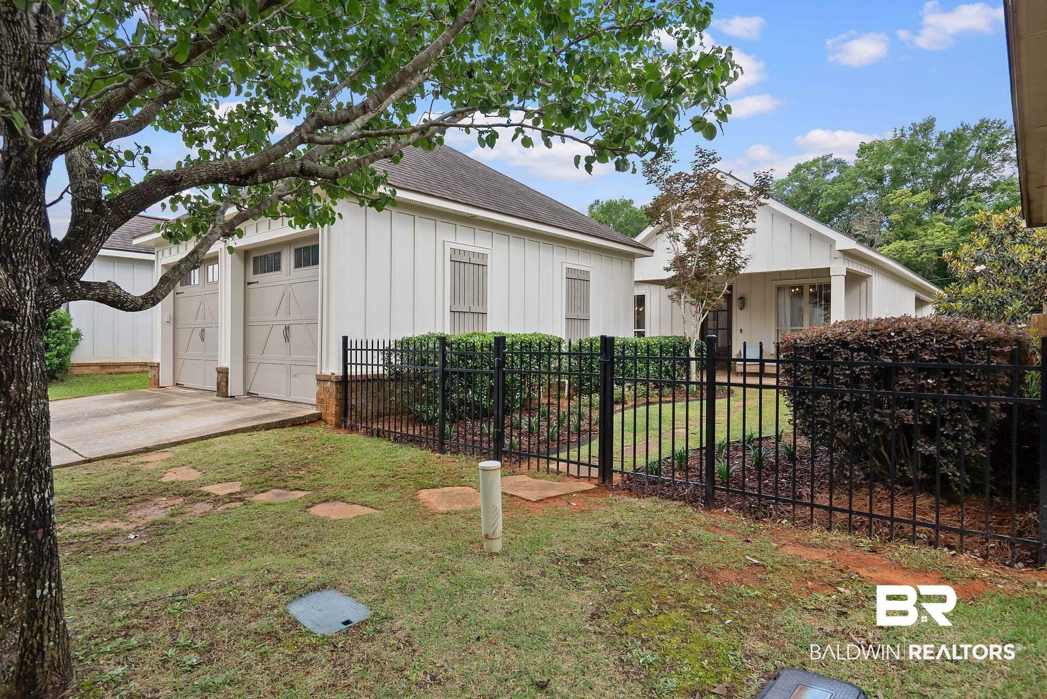 Image 2: Contemporary architecture with board and batten siding, a two-car garage with carriage-style doors, and an iron picket fence enclosing a landscaped courtyard