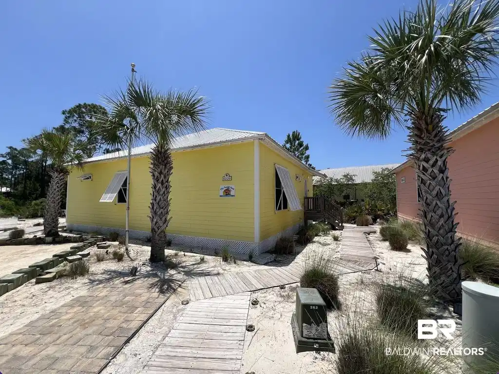 Image 1: Bright yellow siding with a metal roof and louvered window awnings