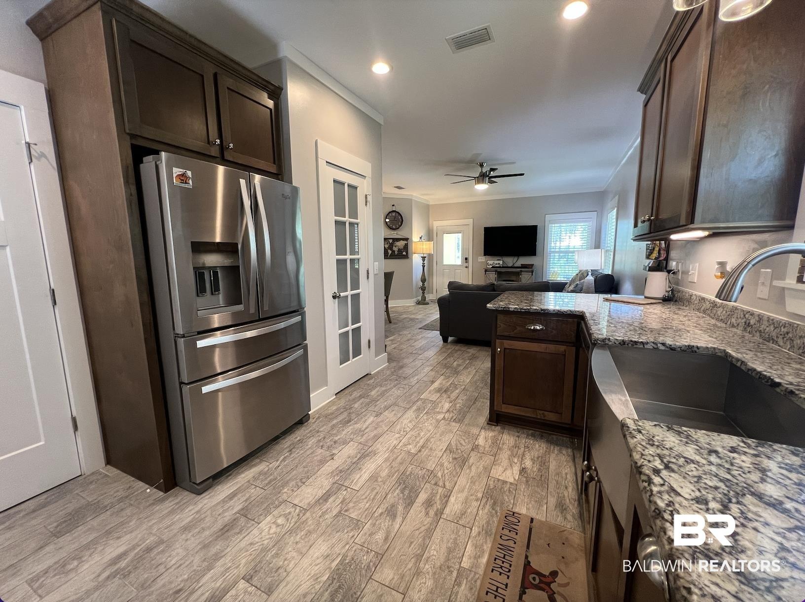 Image 3: Kitchen featuring wood-finish flooring, dark wood cabinetry, and speckled countertops