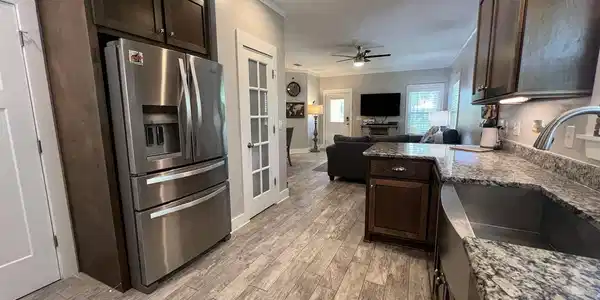 Image 3: Kitchen featuring wood-finish flooring, dark wood cabinetry, and speckled countertops