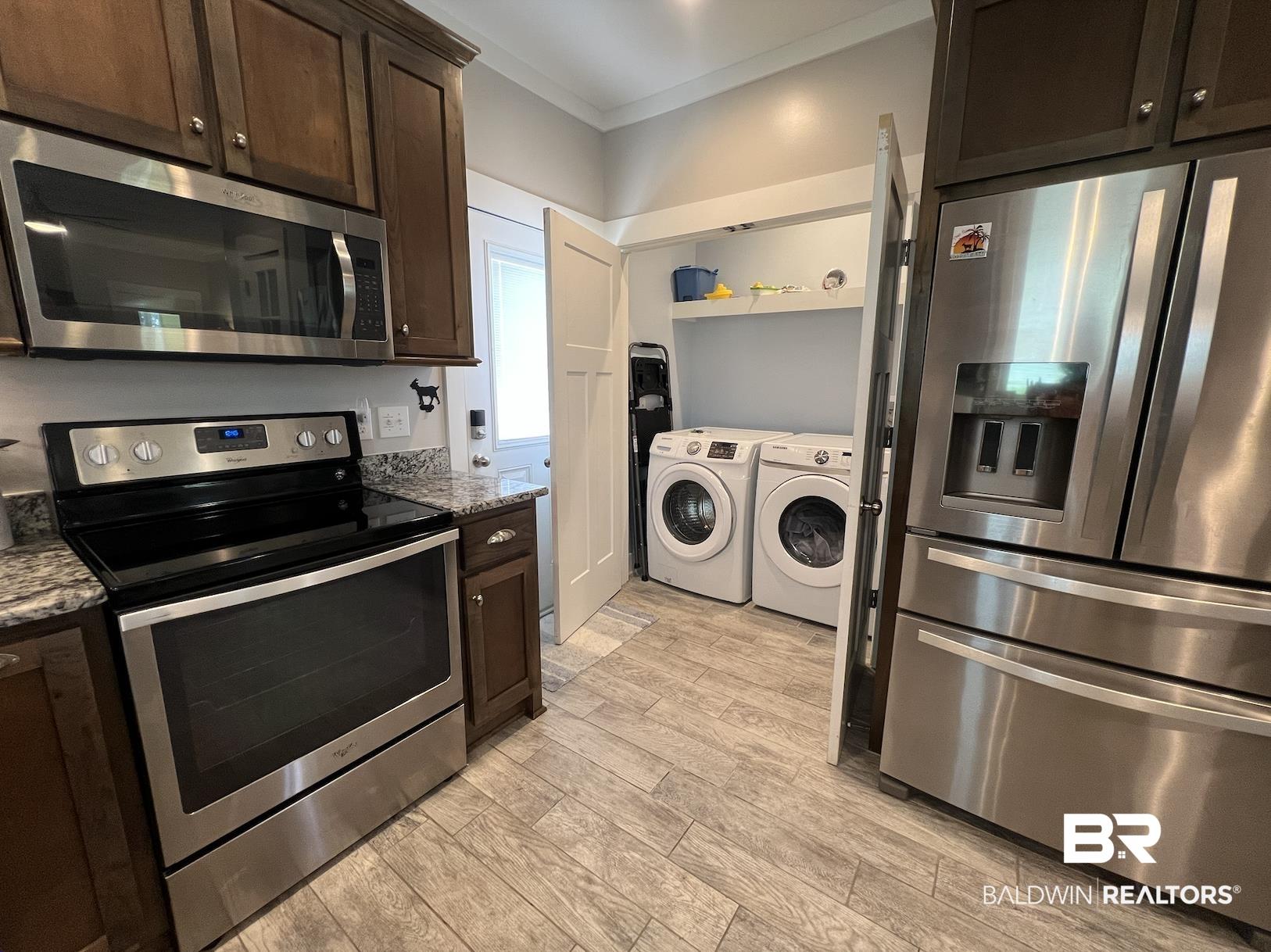 Image 4: Kitchen featuring dark wood cabinetry, stainless steel appliances, granite countertops, and wood-finish flooring