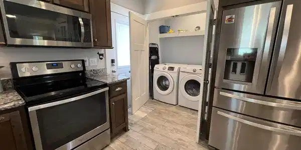 Image 4: Kitchen featuring dark wood cabinetry, stainless steel appliances, granite countertops, and wood-finish flooring