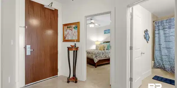 Image 3: Entry foyer featuring a wood-finish door with a door closer, tile flooring, and white baseboards