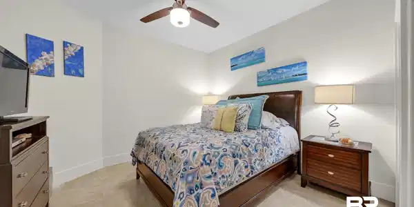 Image 4: Bedroom featuring neutral wall paint, tile flooring, a dark wood ceiling fan with integrated lighting, and white baseboards