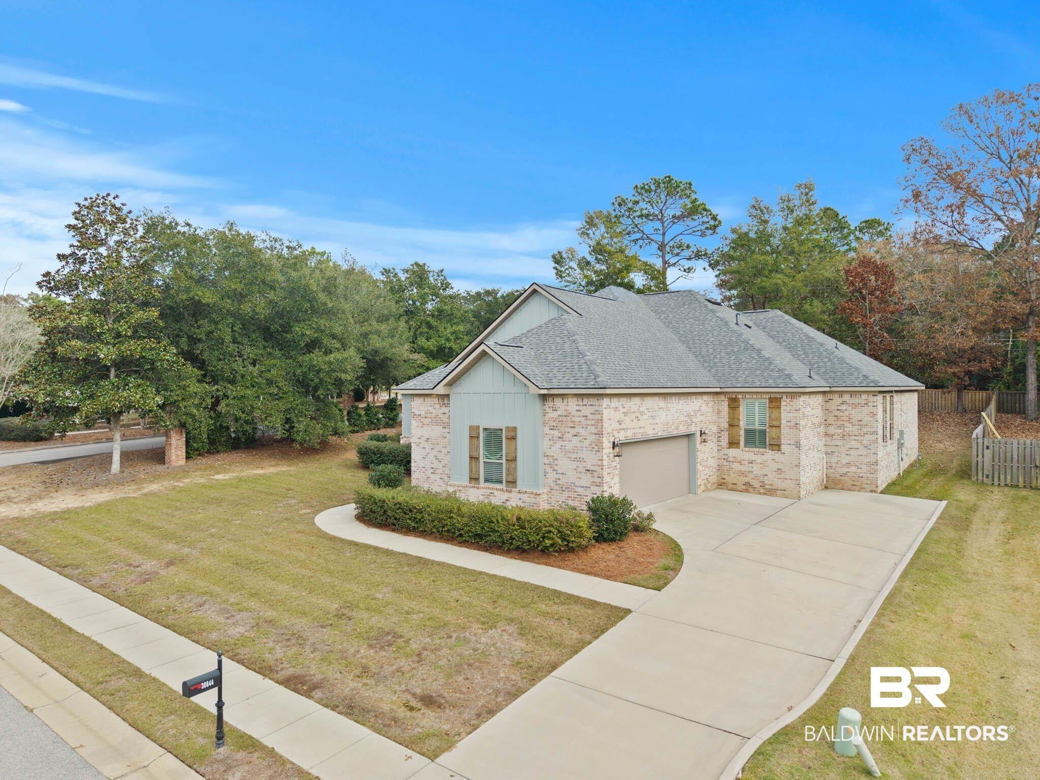 Image 4: View of side of home with roof with shingles, driveway, brick siding, and an attached garage