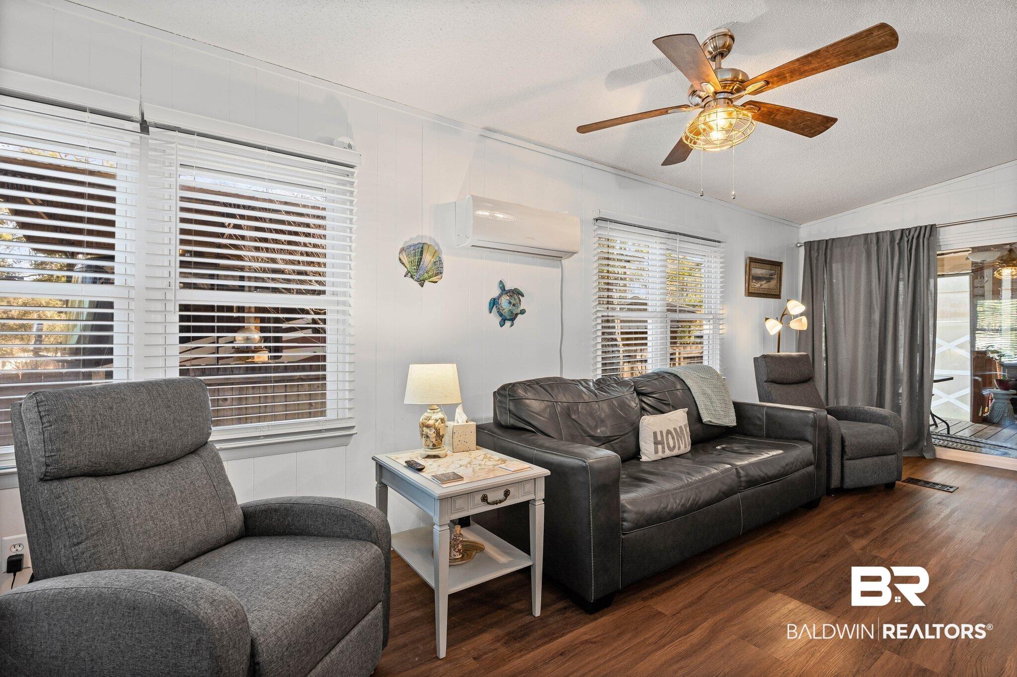 Image 3: Living room with wood finished floors, a textured ceiling, vaulted ceiling, a ceiling fan, and a wall mounted AC