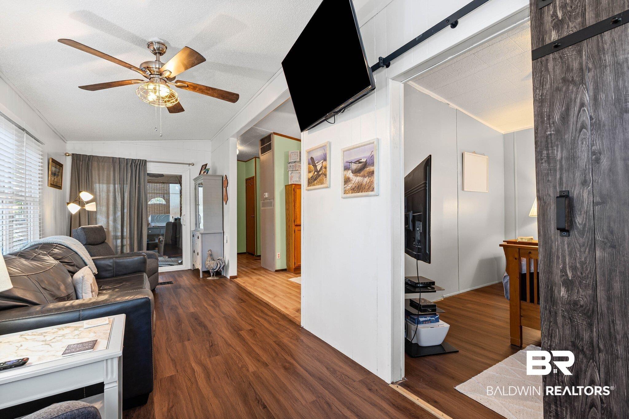 Image 4: Living room featuring a barn door, vaulted ceiling, dark wood-style floors, and ceiling fan