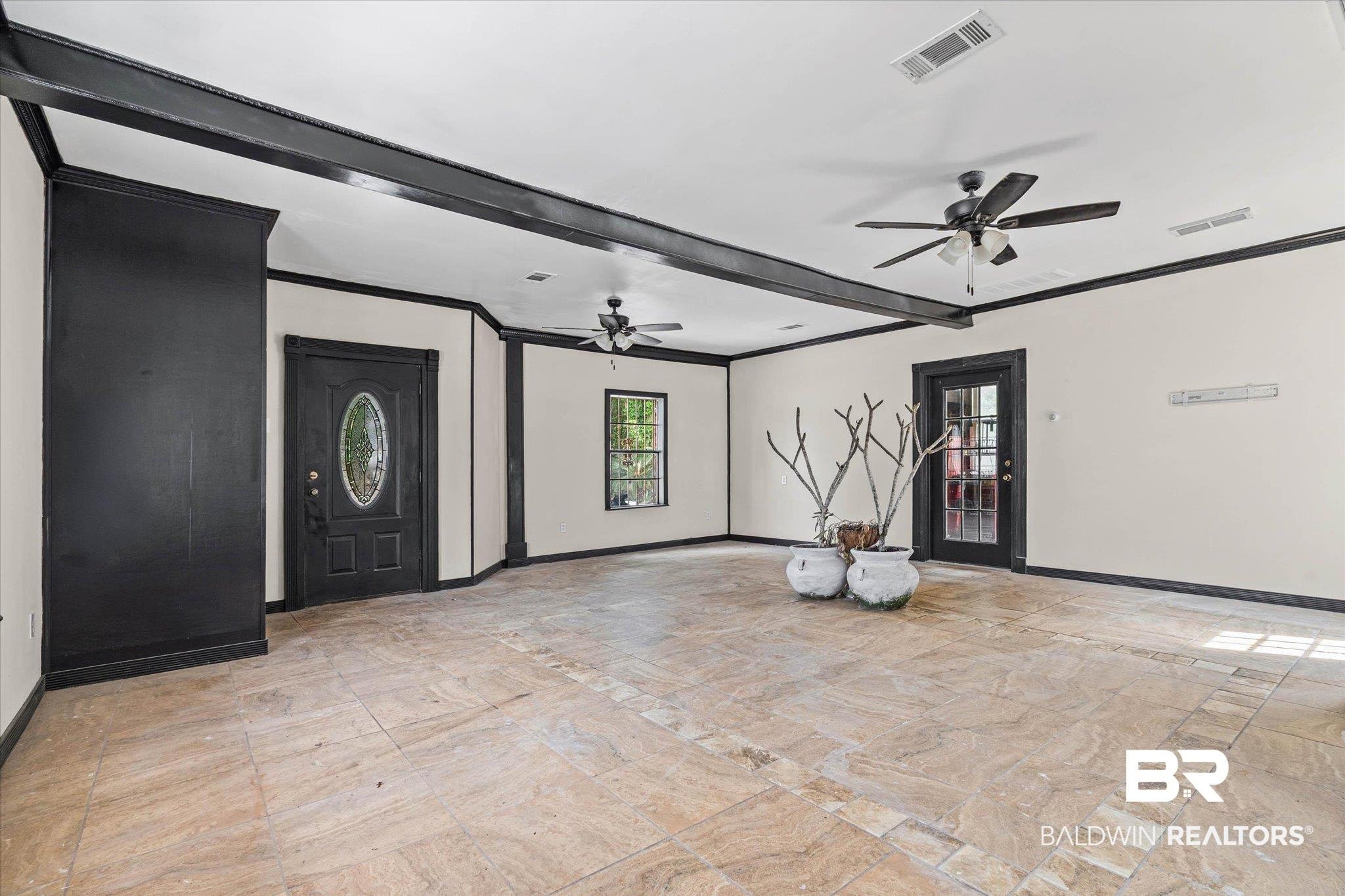 Image 3: Spacious room featuring large format tile flooring with a perimeter accent, black trim, and ceiling beams