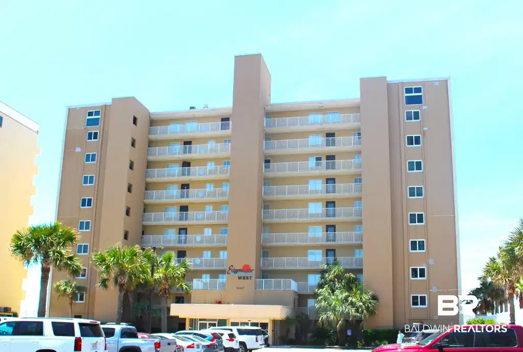 Image 1: Multi-story condominium building featuring a tan stucco exterior and numerous private balconies with white railings