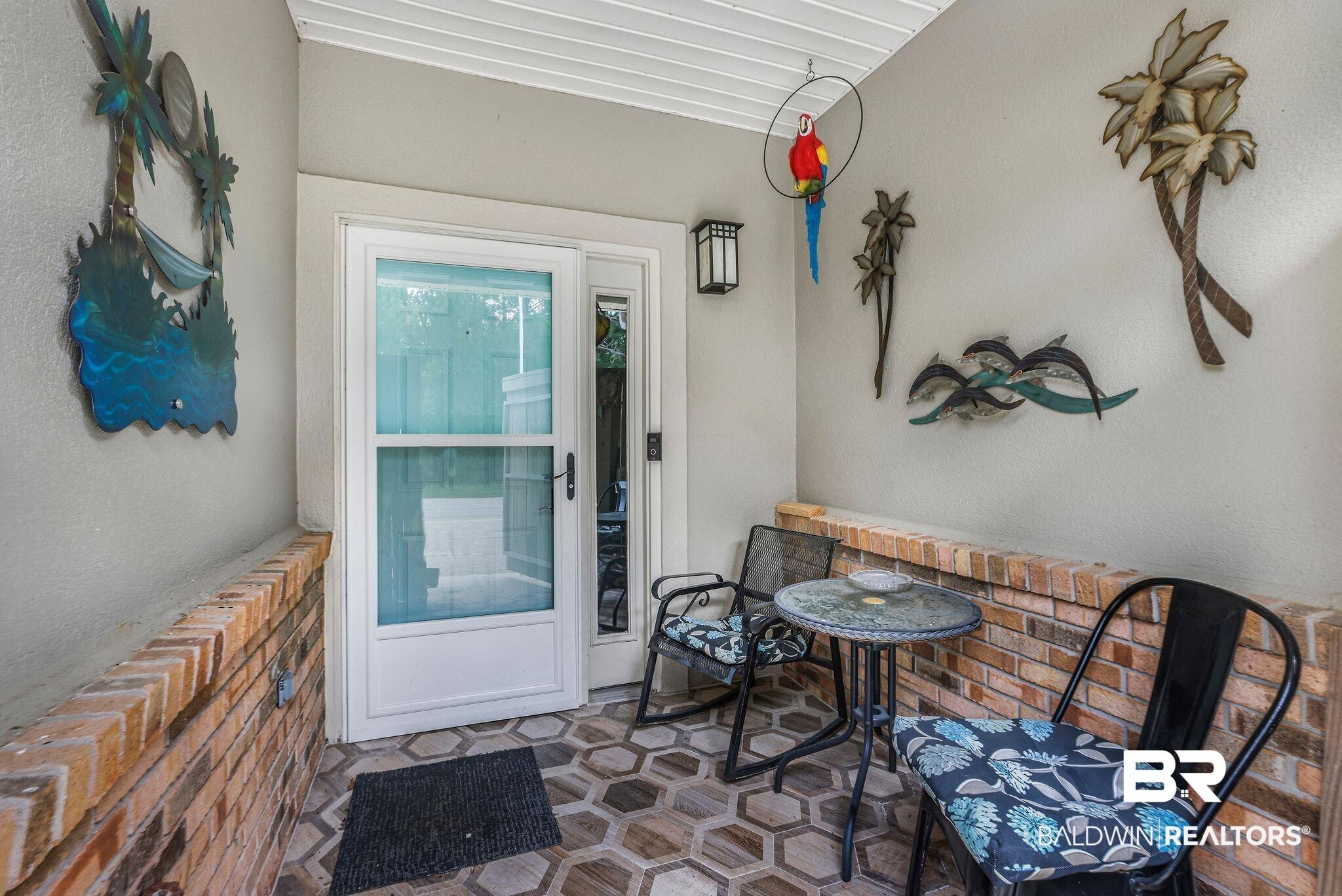 Image 2: Enclosed front entryway featuring a white storm door, hexagonal tile flooring, and a brick half-wall