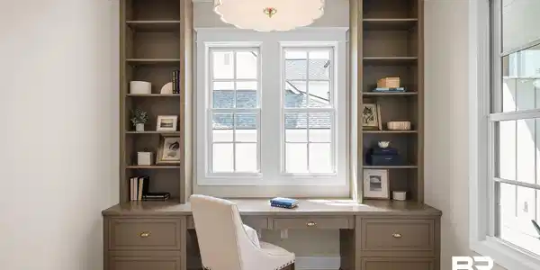 Image 2: Built-in workstation featuring a desk with integrated drawers, flanking vertical shelving, and a scalloped ceiling light fixture