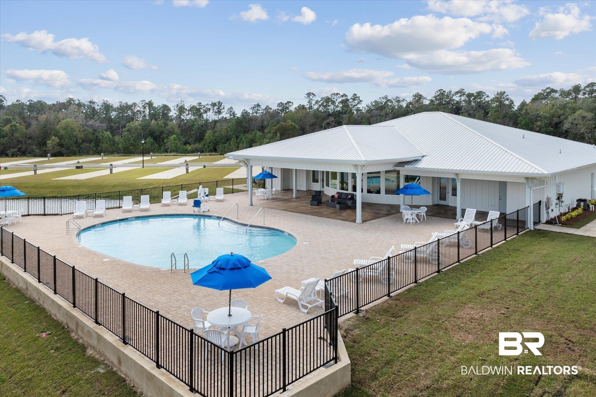 Image 2: Community pool with a patio area and view of wooded area
