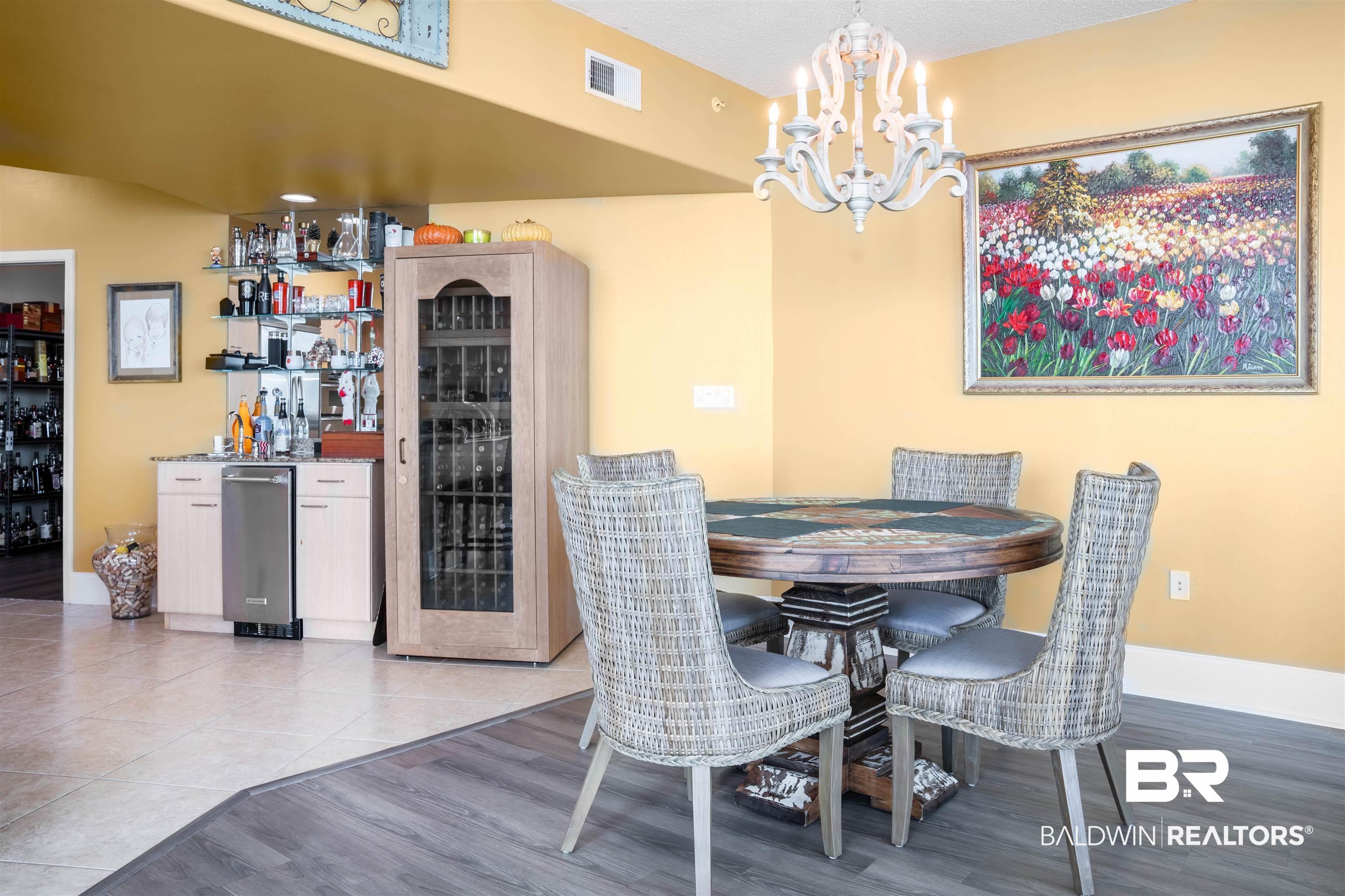 Image 4: Dining room with bar area, a chandelier, and light wood-type flooring