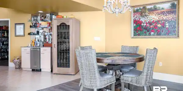 Image 4: Dining room with bar area, a chandelier, and light wood-type flooring