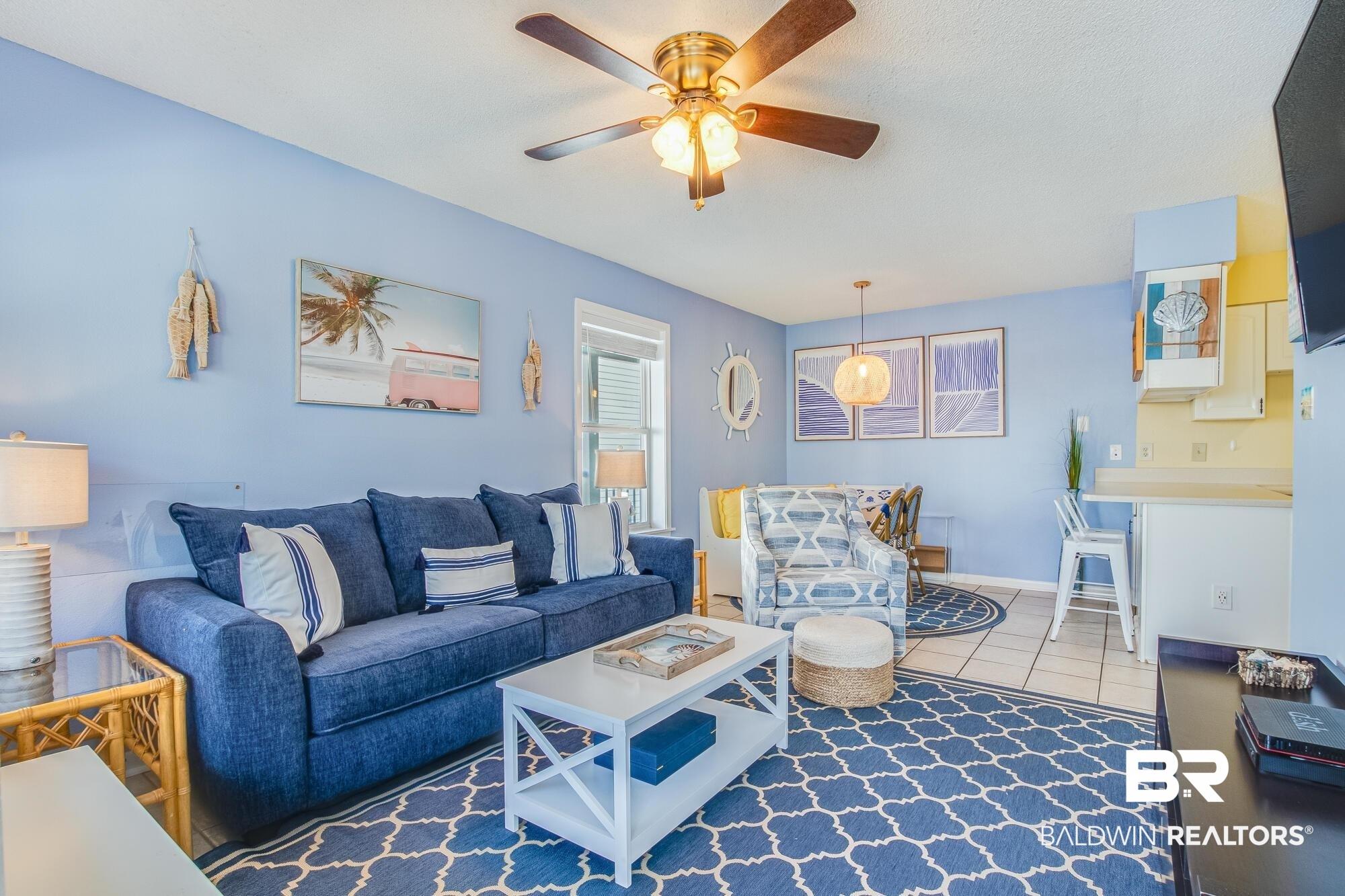 Image 2: Open-concept living space with light blue walls, tile flooring, and a ceiling fan