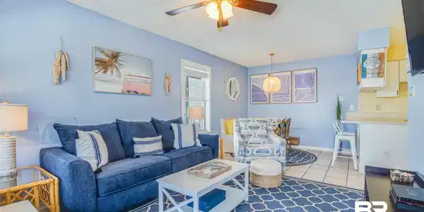 Image 2: Open-concept living space with light blue walls, tile flooring, and a ceiling fan