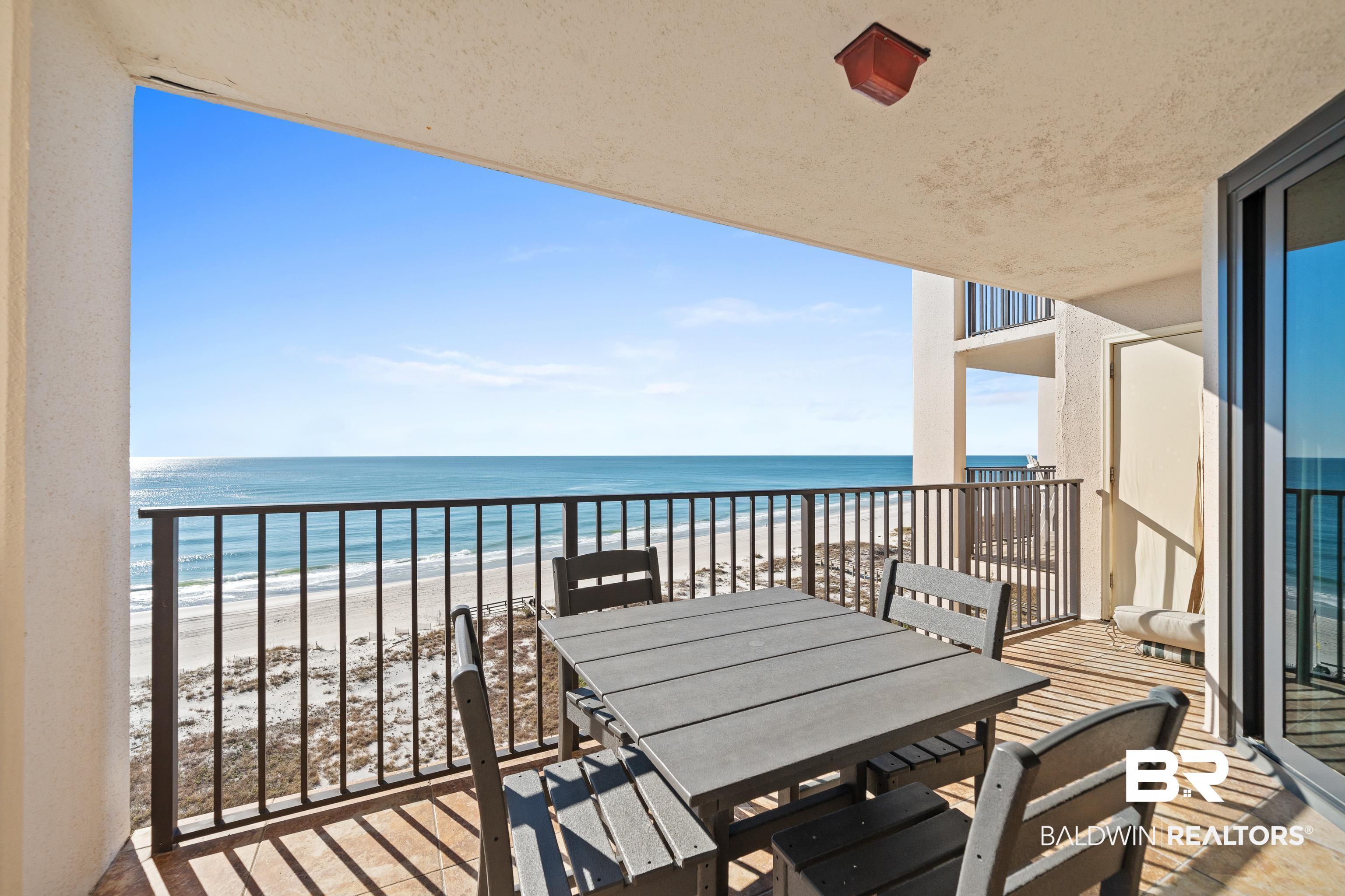 Image 4: Balcony with outdoor dining area and view of water and beach