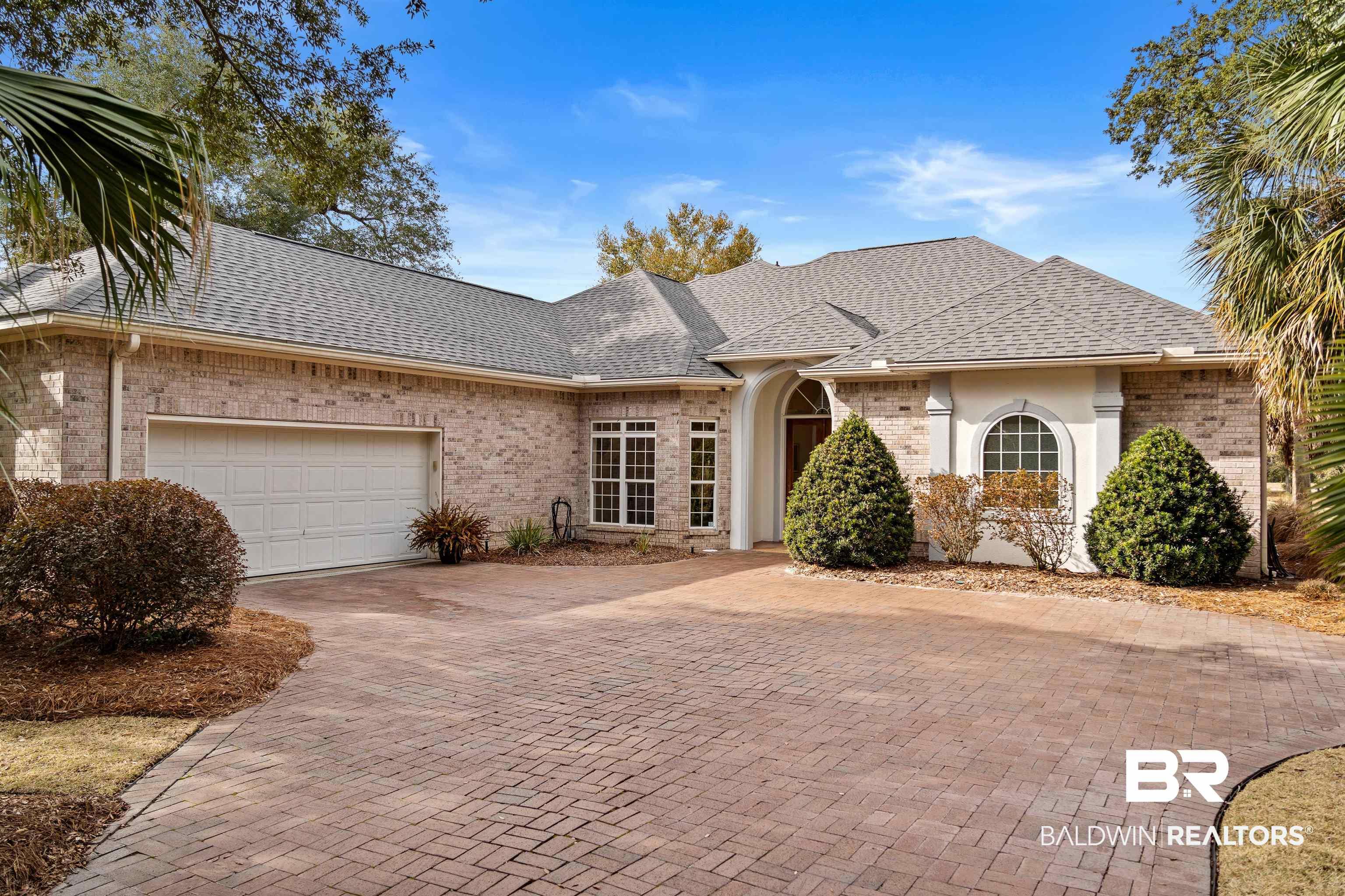 Image 4: View of front facade featuring brick siding, roof with shingles, decorative driveway, and a garage