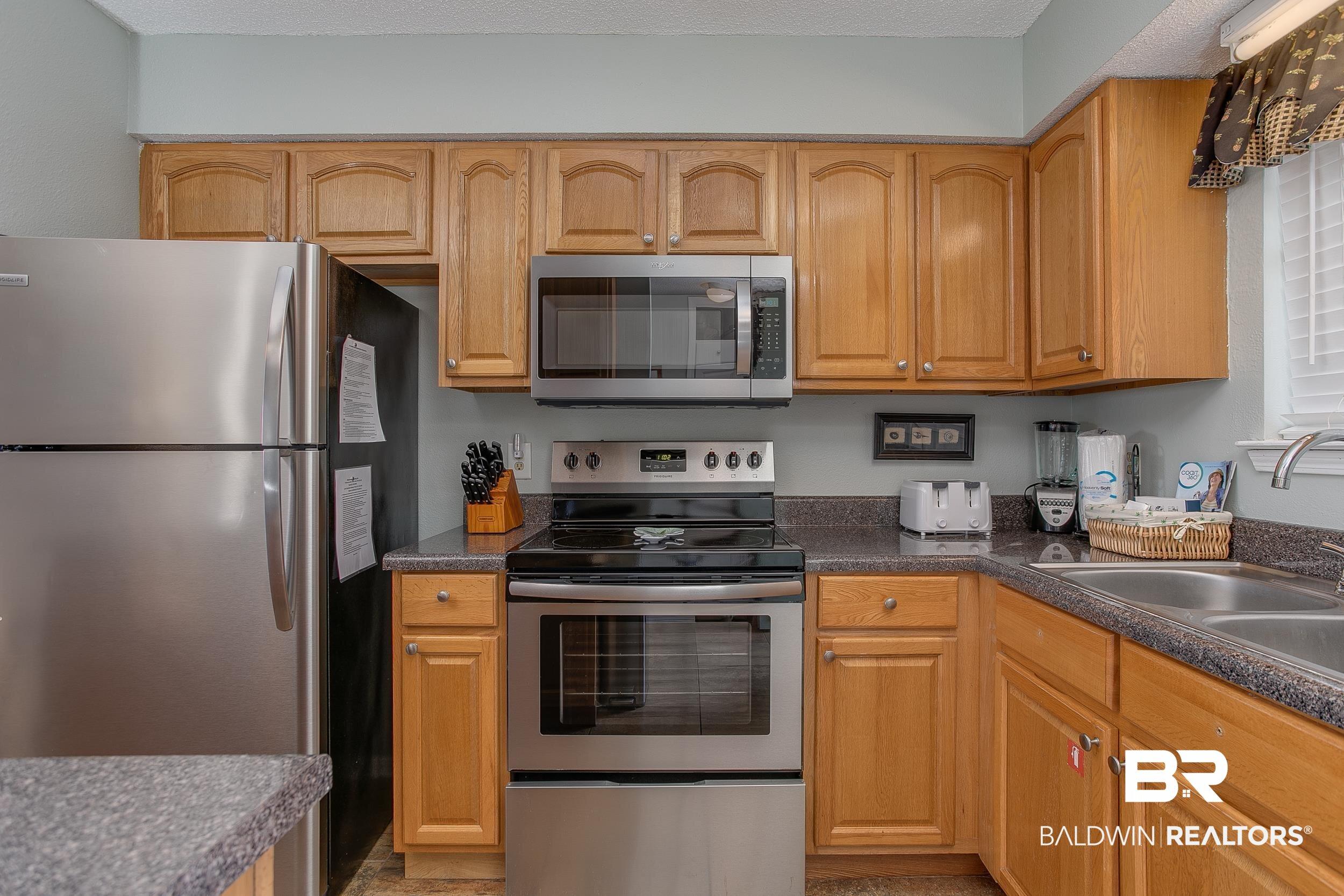 Image 4: Kitchen featuring appliances with stainless steel finishes and dark countertops