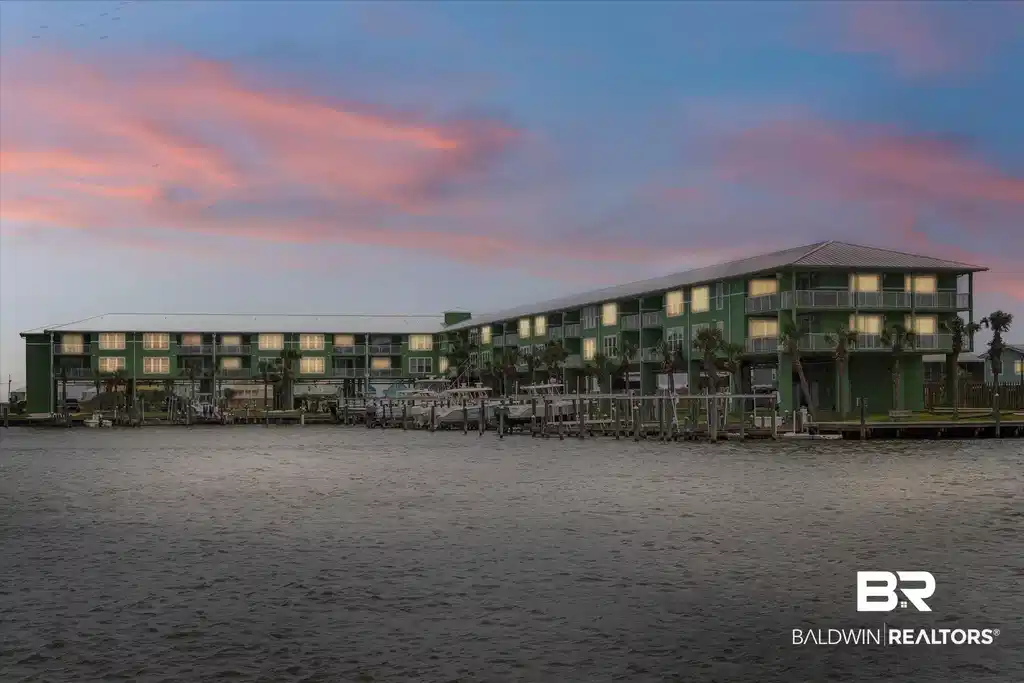 Image 1: Multi-story waterfront building featuring an expansive dock system with multiple boat slips, individual unit balconies, and mature palm trees