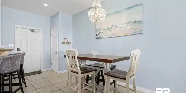 Image 3: Casual dining area featuring a crystal chandelier, light blue wall paint, and tile flooring