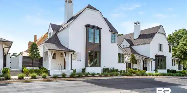 Image 2: View of front of home with a chimney, a gate, roof with shingles, and stucco siding