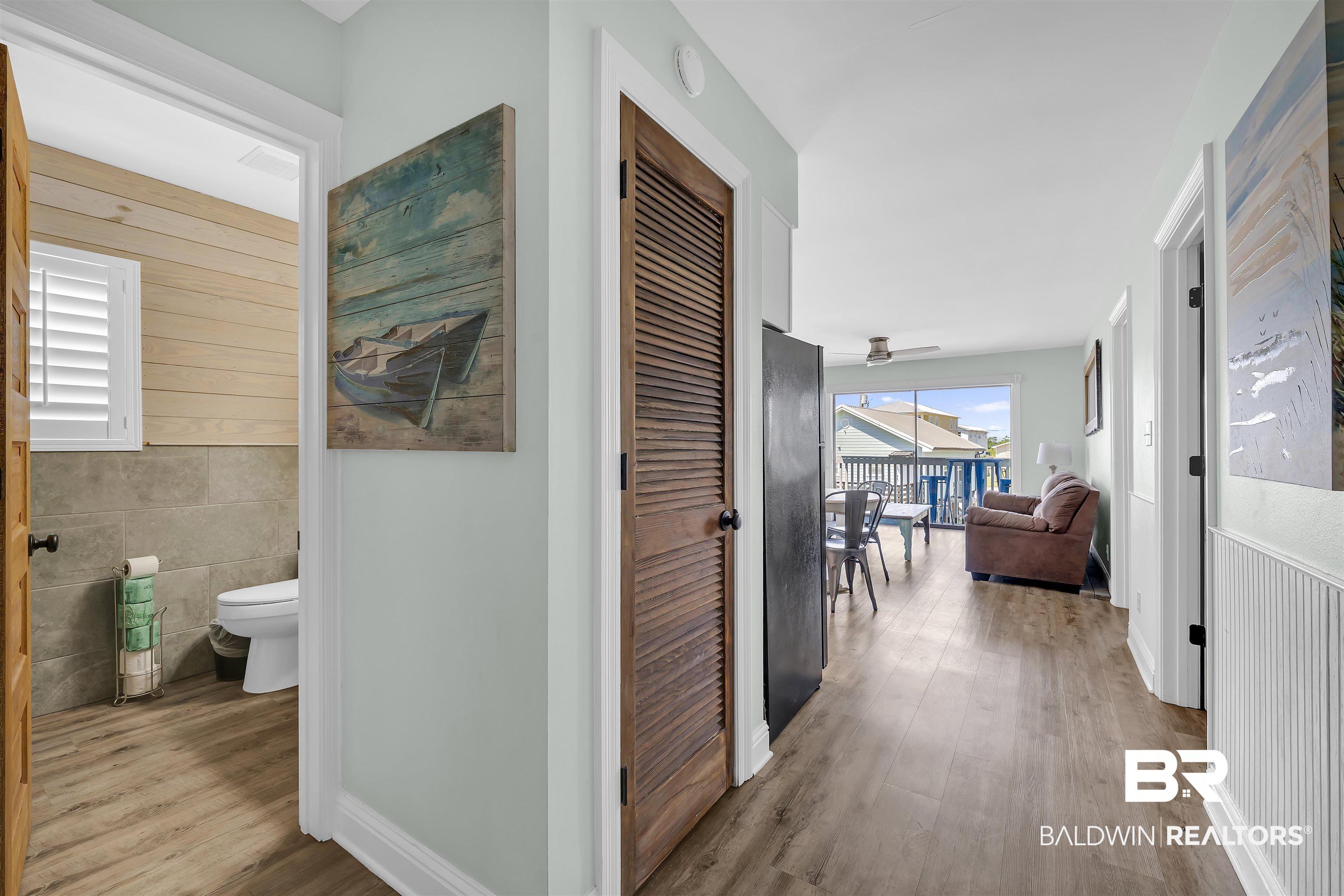Image 2: Corridor featuring wood finished floors, tile walls, wainscoting, and wood walls